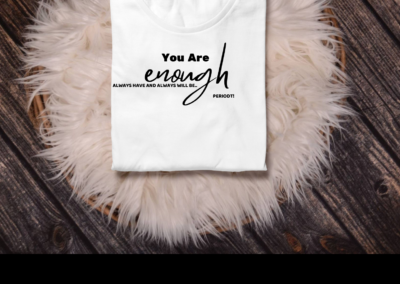 White tee with black font- You are Enough- on top of a pink rug