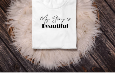 White shirt with black font- my story is beautiful on top of a pink fury rug.